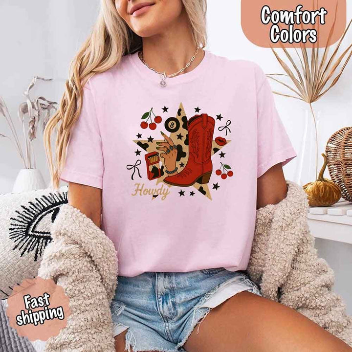 May include a short-sleeve comfort shirt with the phrase “Howdy Cowgirl” displayed in a bold Western-style font, featuring a star collage design with assorted colors for a playful and rustic look.