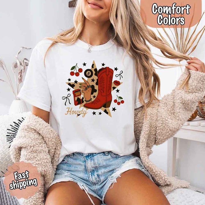 May include a short-sleeve comfort shirt with the phrase “Howdy Cowgirl” displayed in a bold Western-style font, featuring a star collage design with assorted colors for a playful and rustic look.
