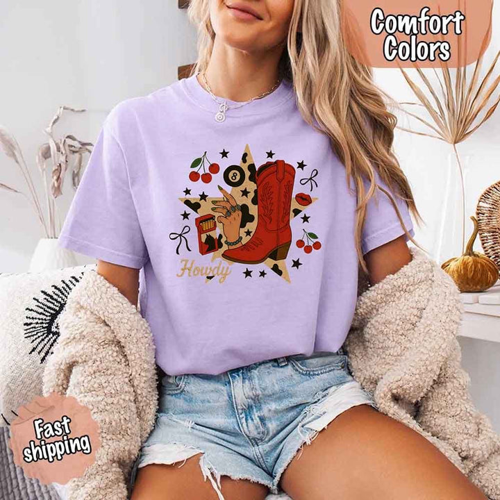 May include a short-sleeve comfort shirt with the phrase “Howdy Cowgirl” displayed in a bold Western-style font, featuring a star collage design with assorted colors for a playful and rustic look.