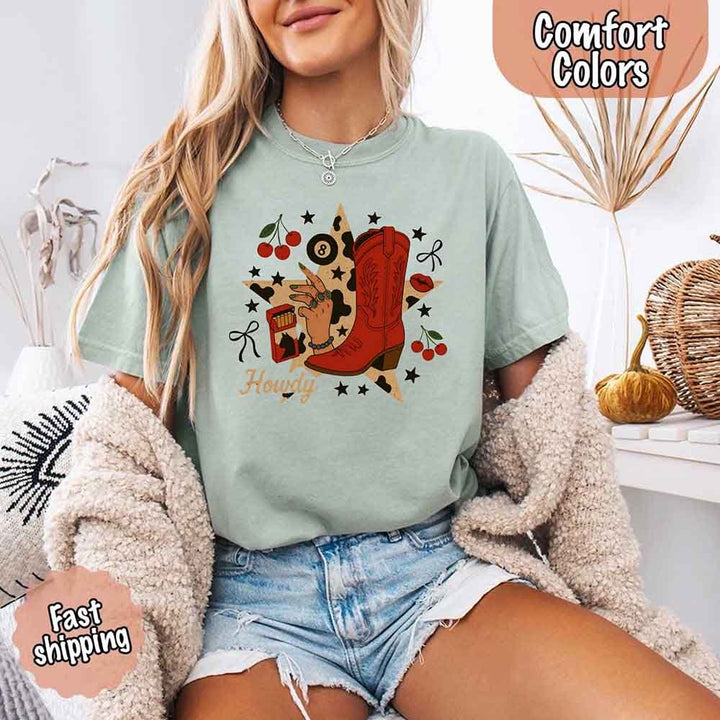 May include a short-sleeve comfort shirt with the phrase “Howdy Cowgirl” displayed in a bold Western-style font, featuring a star collage design with assorted colors for a playful and rustic look.